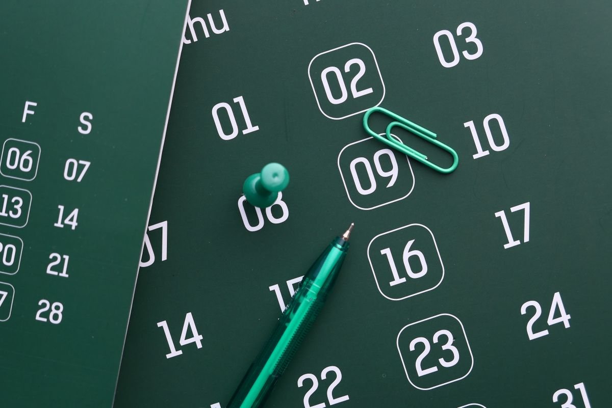 カレンダーの日付がいくつも四角で囲まれ、そばにペンとクリップが置かれている。通う日を数える場面のイメージ