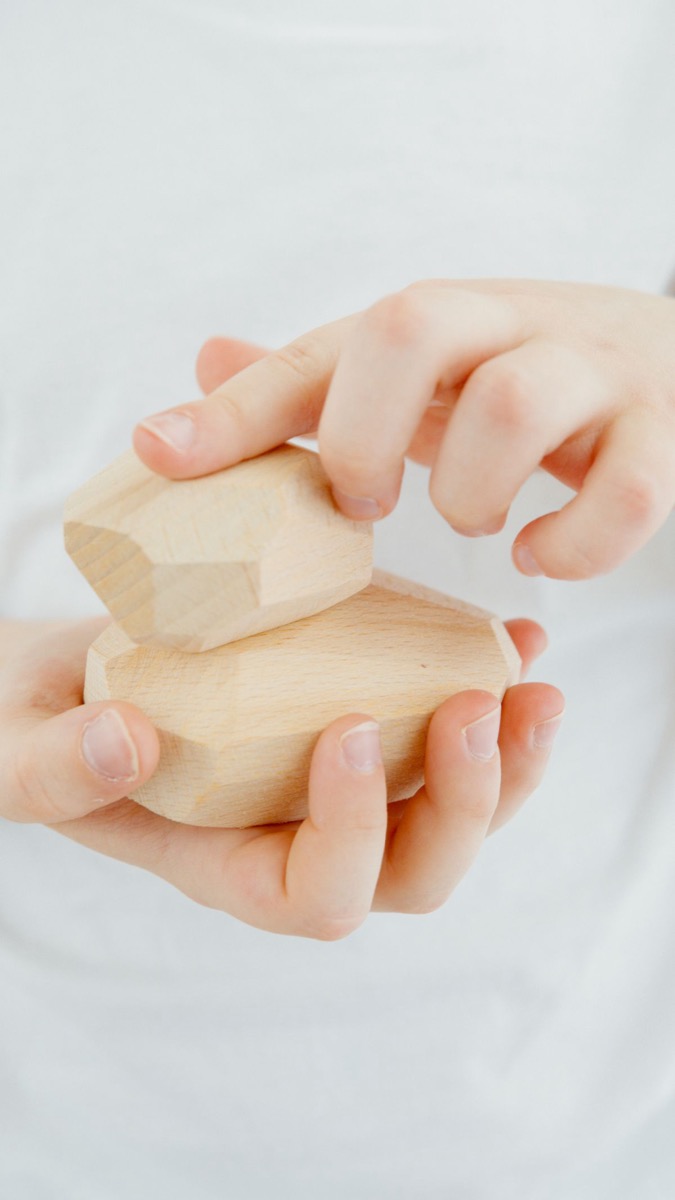 木の積み木を両手で重ねる子どもの手元。発達検査では積み木を使った課題が出されることがある