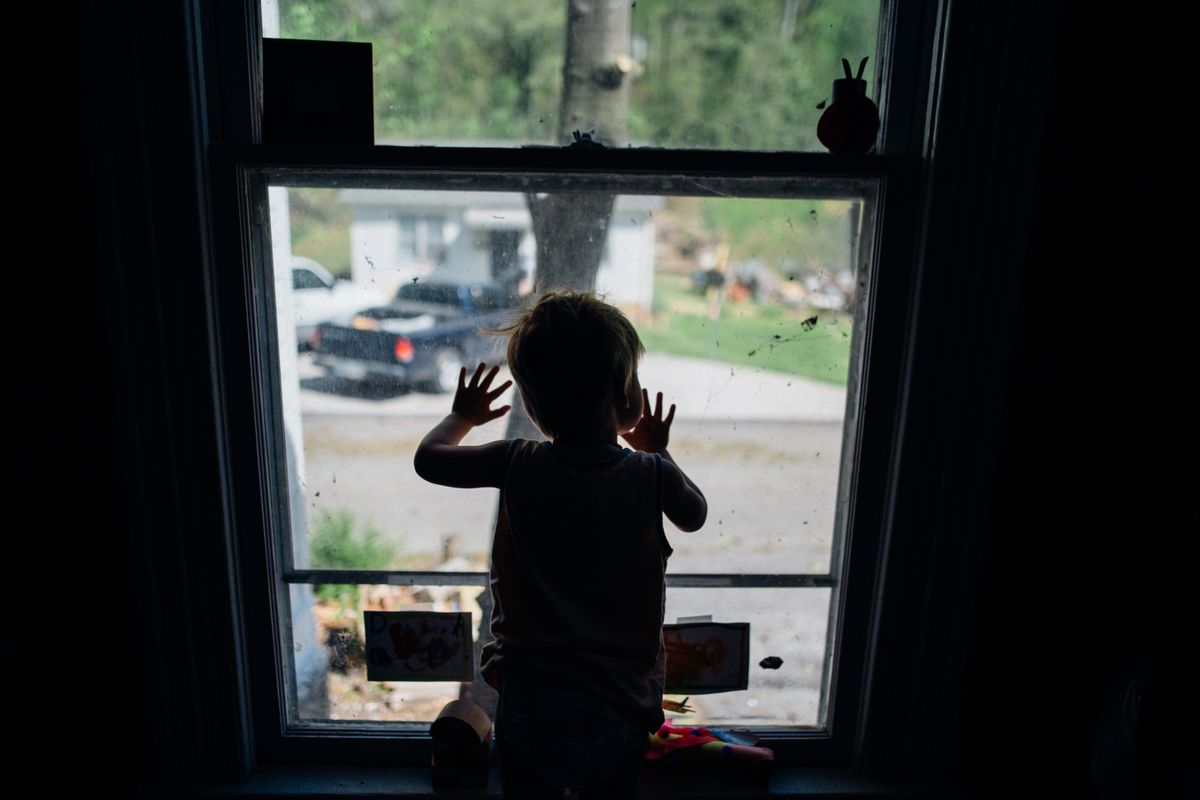 窓ガラスに手をついて外を見ている子どもの後ろ姿。理由を言葉にできないまま、行きたくない気持ちだけが残っている場面のイメージ