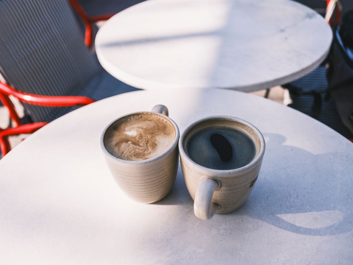 陽の差すカフェの丸テーブルに2つのカップが並び、同じ立場の人と向かい合って話す時間を思わせる場面