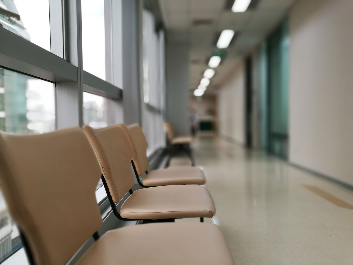 窓に沿って並ぶ人のいない待合いす。初回の面談や診察を待つ場面のイメージ