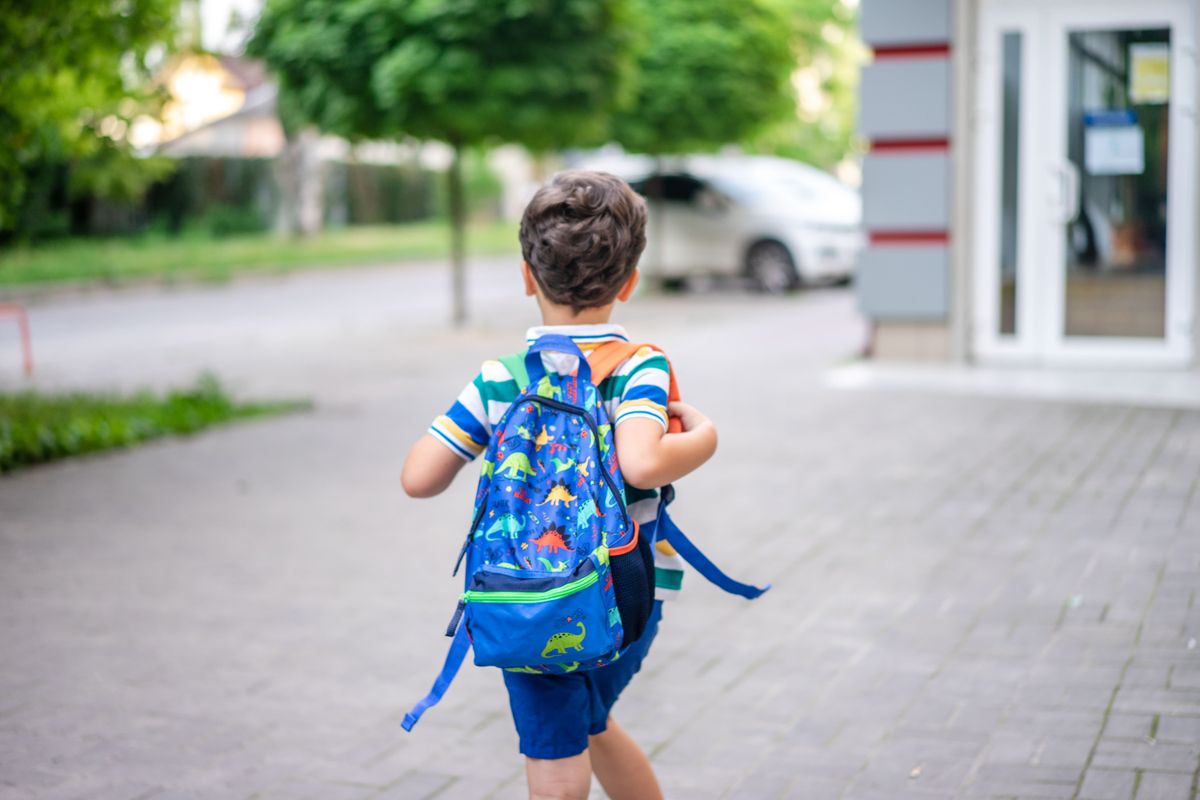 リュックを背負って歩く子どもの後ろ姿。持ち物を抱えて登下校する場面のイメージ